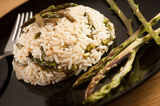 Rice with wild asparagus on a blavk plate with fork served on a