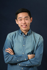 Obraz premium Smiling young Asian man with crossed hands looking at camera