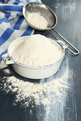 Sifting flour through sieve on wooden table, closeup