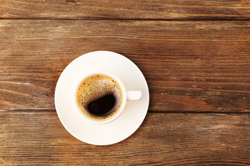 Cup of coffee on wooden table, top view