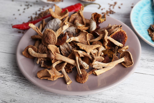 Dried mushrooms in plate on wooden background
