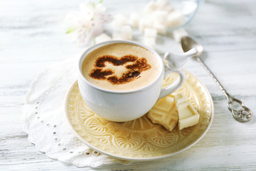 Cup of latte coffee art on wooden table, on light background