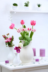 Beautiful composition with different flowers in vases on wall background