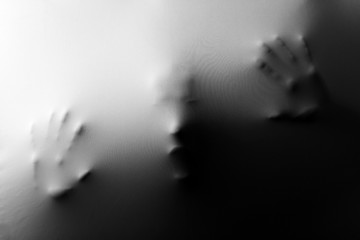 Screaming human face with hands pressing through fabric as horror background