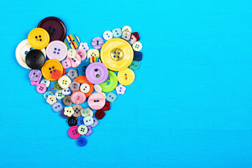 Sewing buttons heart on cloth background