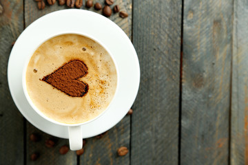 Cup of cappuccino with heart of cocoa on wooden table