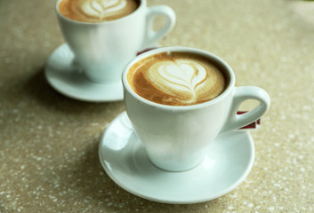 Cups of cappuccino with heart on foam on table in cafe