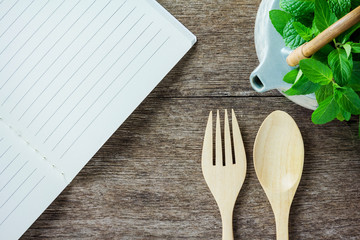 open blank lined notebook. Wooden spoon and forkon
