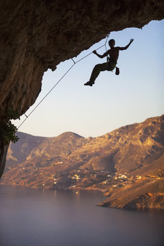 Male rock climber on overhanging cliff, Kalymnos Island, Greece