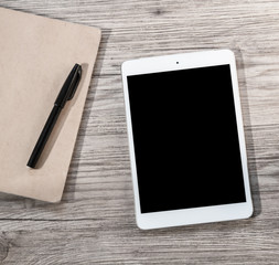 White Tablet with blank black screen on the wooden background