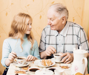 grandfather and granddaughter sitting on the table in kitchen