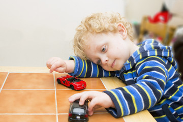 Naklejka premium Boy playing with toy-cars