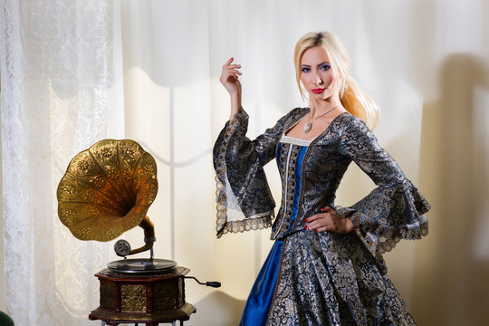 Girl in medieval dress standing next to a gramophone