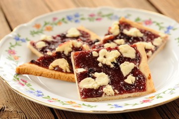 Berry jam cookies in white plate on wooden background closeup