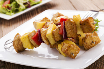 Grilled chicken skewers with pineapple, peppers and onions serve