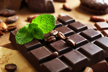 Chocolate with mint, spices and coffee beans on table, closeup