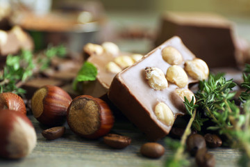 Set of chocolate with nuts, herbs and coffee beans on wooden table, closeup