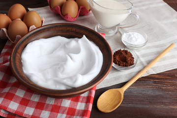 Whipped egg whites and other ingredients for cream on wooden table, closeup