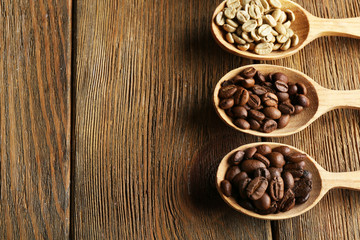 Coffee beans in spoons on wooden background
