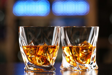 Glasses of whiskey on bar background