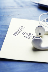 Earphones with text Music - life on sticker on wooden table, closeup