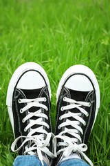 Female feet in gumshoes on green grass background