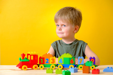 Little boy playing with colorful plastic blocks with numbers.