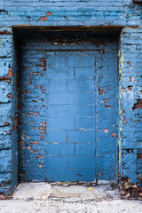 Weathered grungy exterior doorway on abandoned blue building