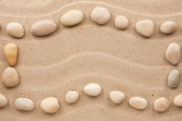 Fototapeta na wymiar Frame made of white stones on a wavy sand