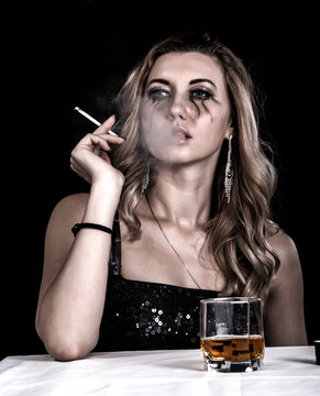 Depressed young woman with a glass of whiskey and a cigarette