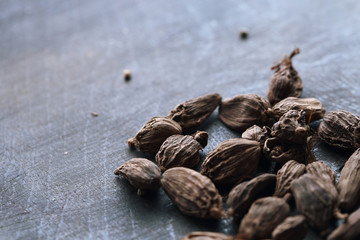 Seeds of black cardamom on the dark wooden table