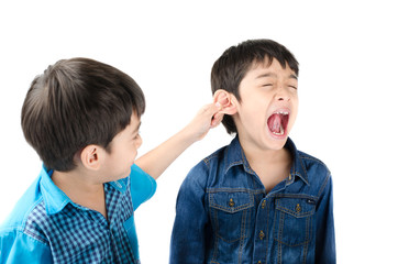 Little sibling boy fighting by pulling ear his brother on white