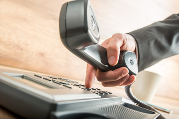 Businessman holding the receiver while dialing
