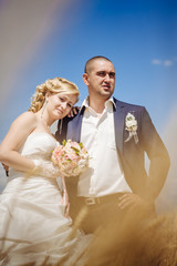 young beautiful wedding couple hugging in a field with grass