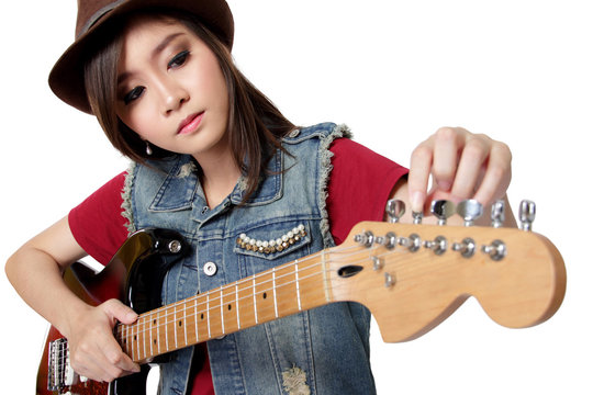 Pretty Asian girl tuning her guitar, on white background