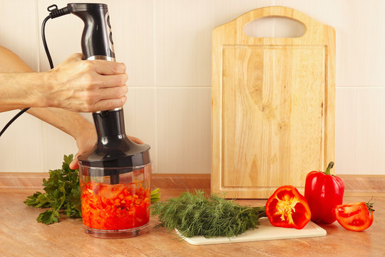 Hands cooks are going to mix red pepper and tomato in a blender