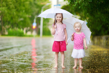 Two cute little sisters on a rainy summer day