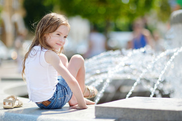 Fototapeta na wymiar Cute little girl playing with a city fountain