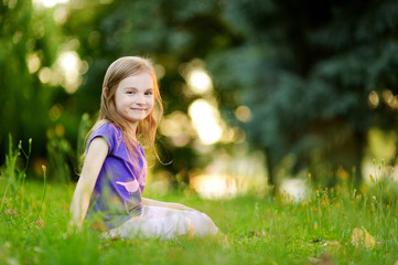 Naklejka na ściany i meble Cute little girl sitting on the grass