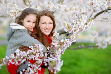 Fototapeta premium Mother and her child in blooming cherry garden