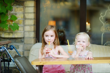 Two sisters drinking juice and eating pastries