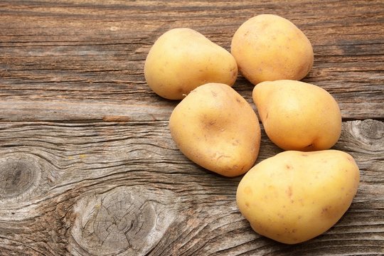 Raw potatoes on a wooden background