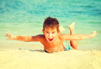 Summer holidays. Joyful boy having fun at the beach