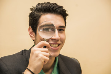Handsome young man holding a magnifying glass