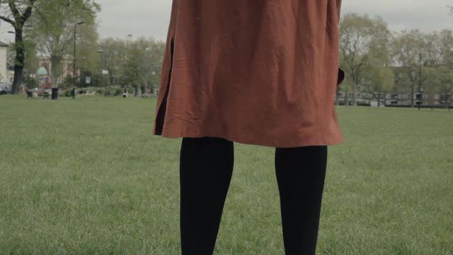 Woman standing in a park with her skirt blowing in the wind