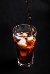 Glass of cola with ice on black background