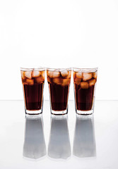 three glasses of cola and ice on a white background. soft drinks