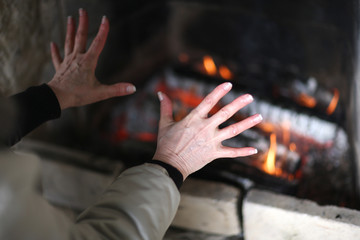 Woman warming her hands by fire at home