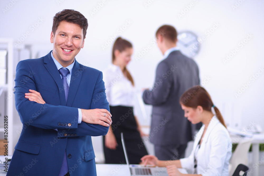 Wall mural Successful business man standing with his staff in background at