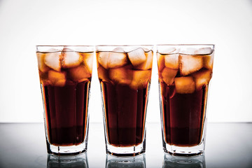 three glasses of cola and ice on a white background. soft drinks